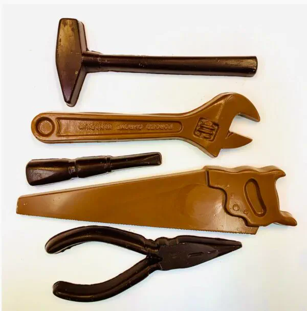 A hammer, wrench, chisel, saw, and pliers made out of milk and dark chocolate.