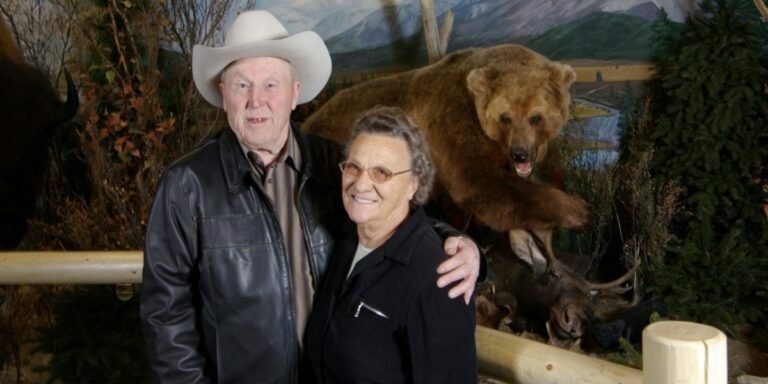 Chester Mjolsness and his wife Martha in front of a taxidermied bear that he donated.