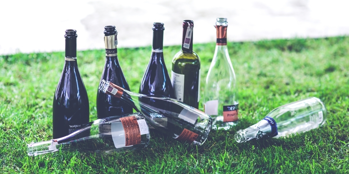 a photo of various bottles on grass next to a sidewalk