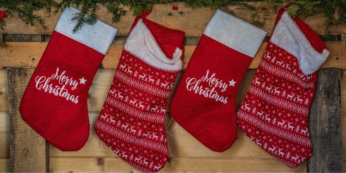 four red Christmas stockings hanging on a wooden wall