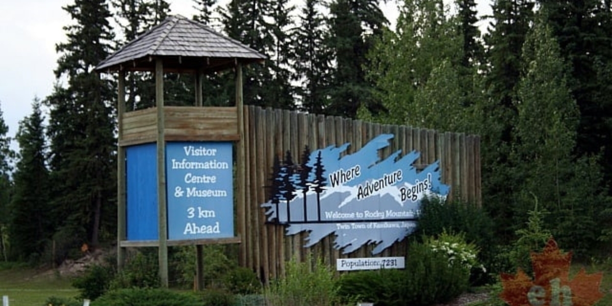 a photo of the entrance to Rocky Mountain House with a large wooden fence and lookout tower surrounded by forest