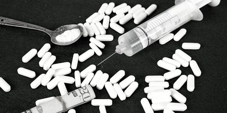 a black and white photo of opioids along with a spoon, syringe, and money on a table