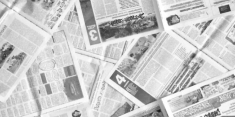a black and white photo of newspapers stacked on top of each other in a pile