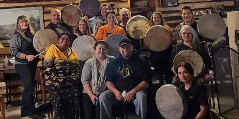 a group of Kokum's Outreach visitors posing for a photo holding the drums they made