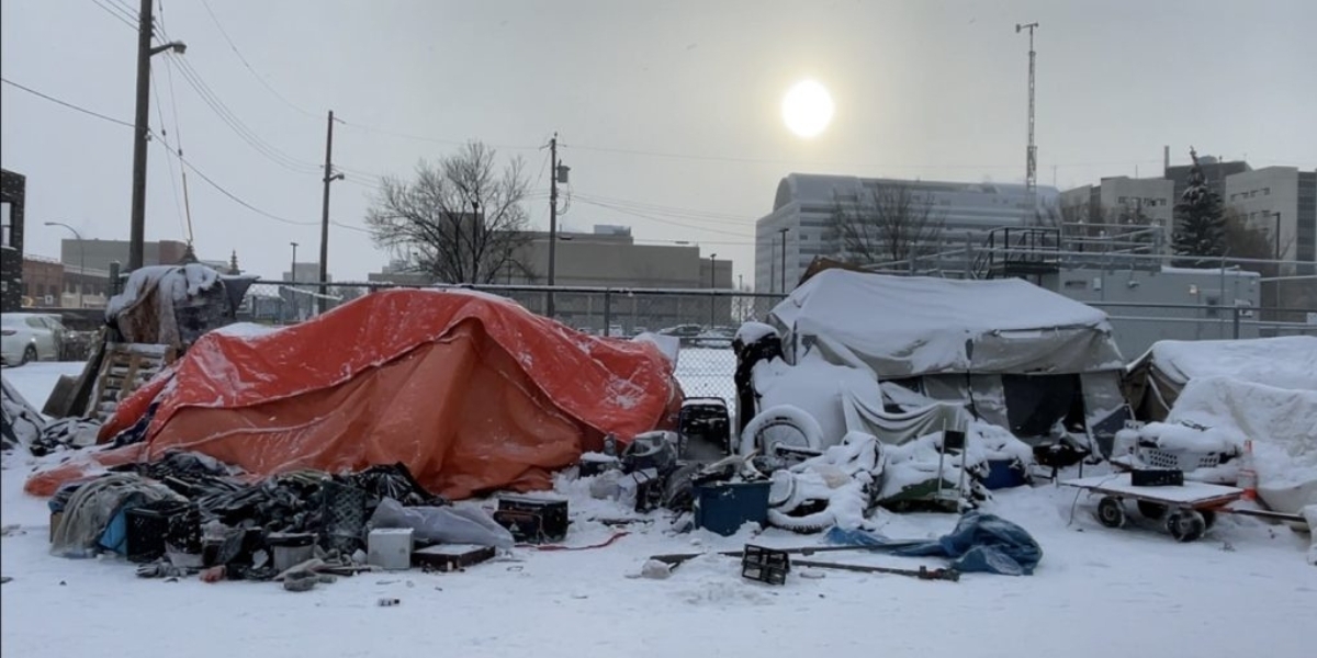 a homeless encampment in Edmonton covered in snow with the city in the background