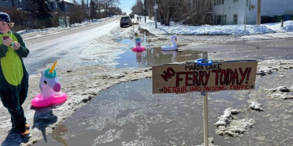 a photo taken by Jamie Ruff of the flooded intersection decorated with a few pool floaties and a sign reading Marda Lake