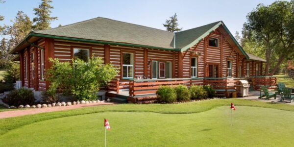 the luxurious mulligan cabin showing off its massive size with muskoka chairs outside and a miniature putting course