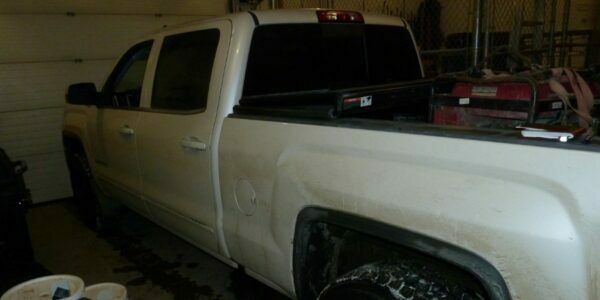 The stolen white GMC Sierra truck in a garage with stolen goods like a generator in the pickup bed
