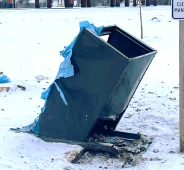 a green garbage bin that was destroyed by a pipe bomb and looks disfigured