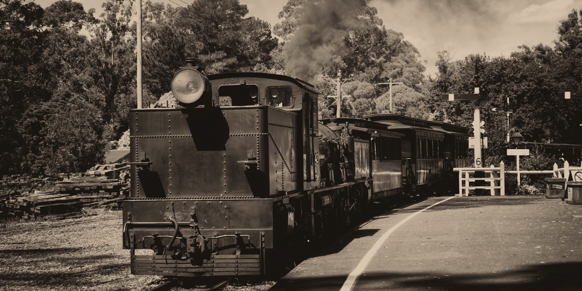 A sepia tone image of an old train with smoke bellowing from the top of the train