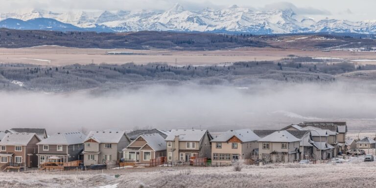 a beautiful shot of Cochrane Alberta with houses at the forefront and the Rocky Mountains in the background