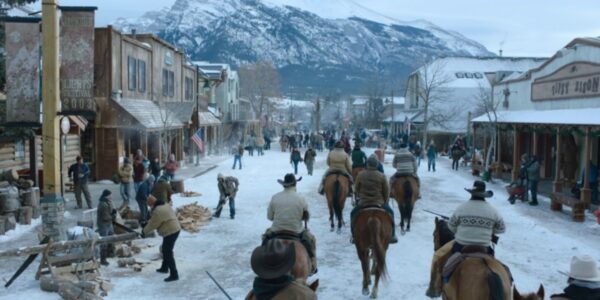 a road view of the jackson community in the last of us covered in snow with members of the community riding horses and the rockies in the background
