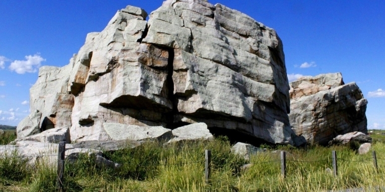 a photo of big rock in okotoks on green grass