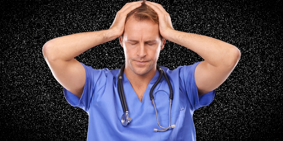 a doctor in blue scrubs holding his head over a background of white noise