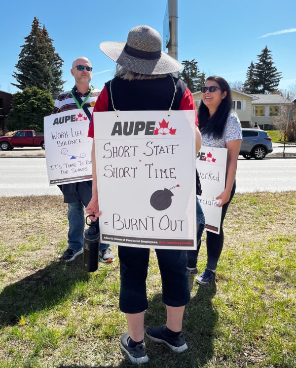 member of the alberta union of provincial employees with a sign at a rally