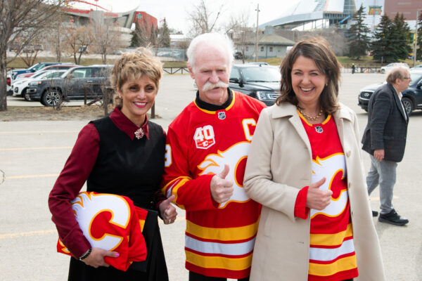 danielle smith posing with the mayor of calgary wearing a calgary flames jersey with her thumb up
