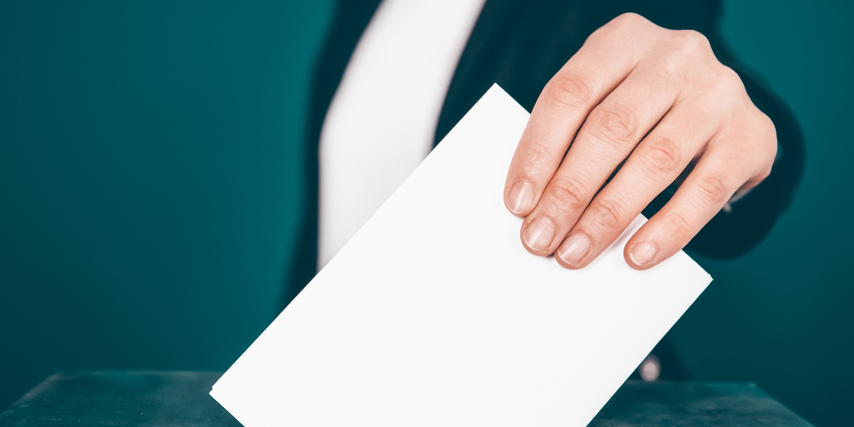 a picture of a woman submitting a ballot into a ballot box