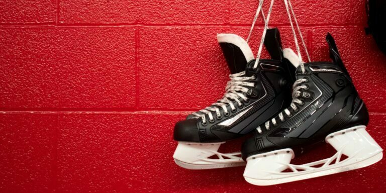 a pair of hockey skates hanging on a red wall