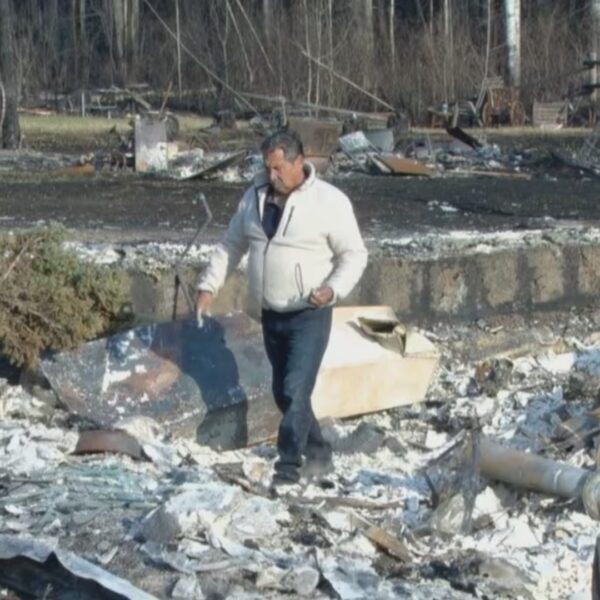 a picture of ron bellerose walking through the burnt debris from a wildfire in his community