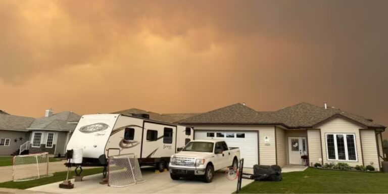 a white house in edson with a white truck and trailer in the driveway with an orange smoke clouded sky above
