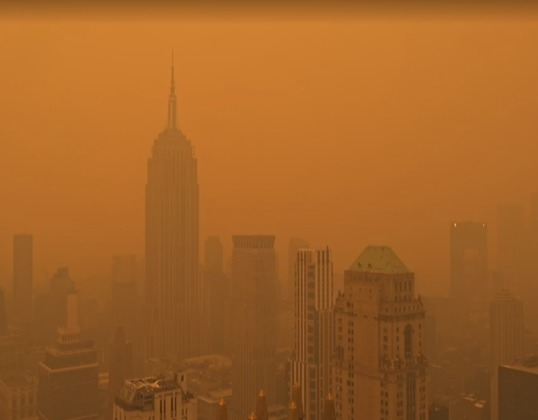 new york city in a dense orange fog due to wildfires in canada