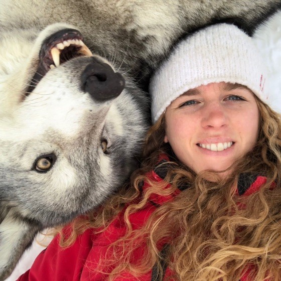 Georgina De Caigny posing for a photo next to a very happy wolfdog