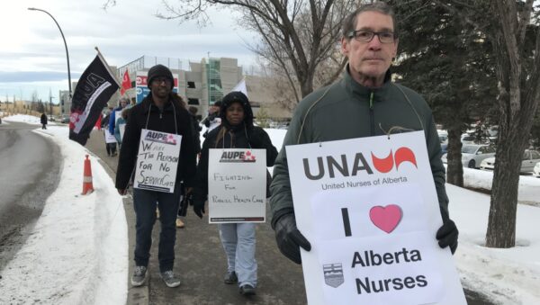 alberta health care workers protesting in the middle of winter holding signs