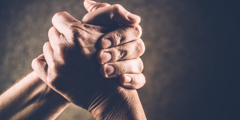 a photo of two hands clasped together for arm wrestling over a brown background