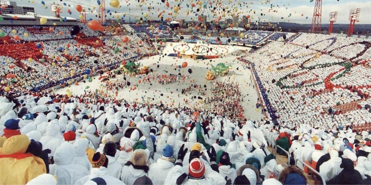 a photo from the 1988 winter olympics in calgary with a dense crowd filling an arena and several balloons floating in the air
