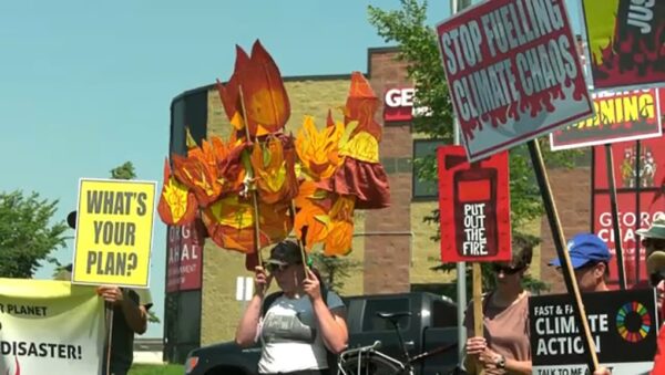 protestors holding signs with one woman holding decorative fire props above her head