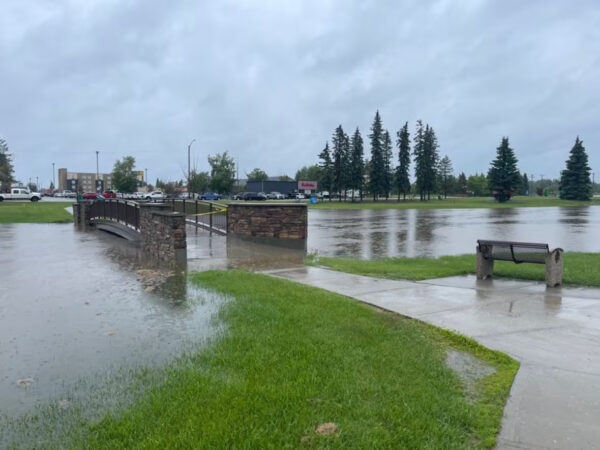 a photo of a bridge in edson with surrounding water as high as the bridge due to flooding