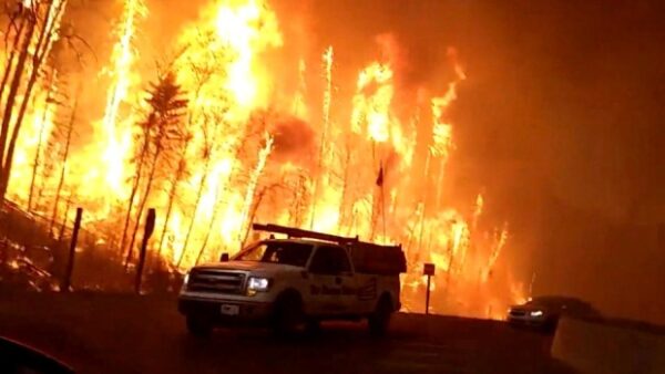 a photo of the fort mcmurray wildfire burning out of control with a truck escaping the flames