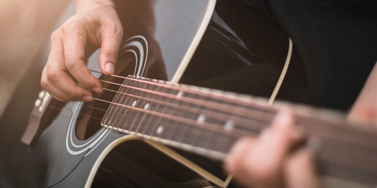 a close up shot of a person playing a black guitar