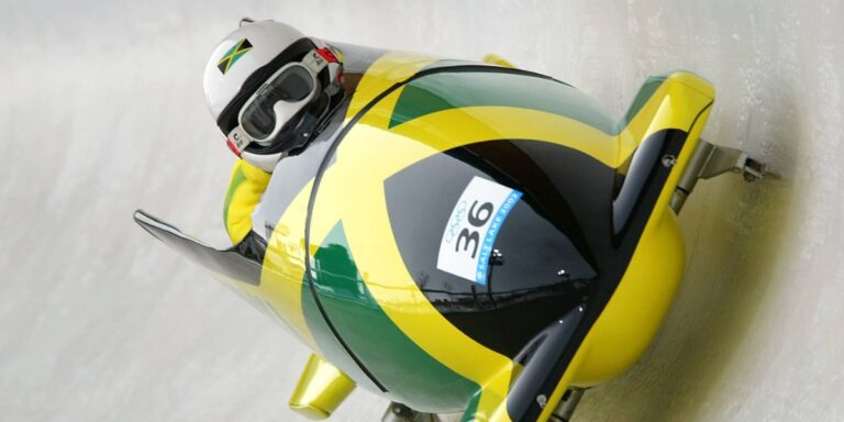 a photo of a bobsledder in a bobsled decorated in the colors of the jamaican flag