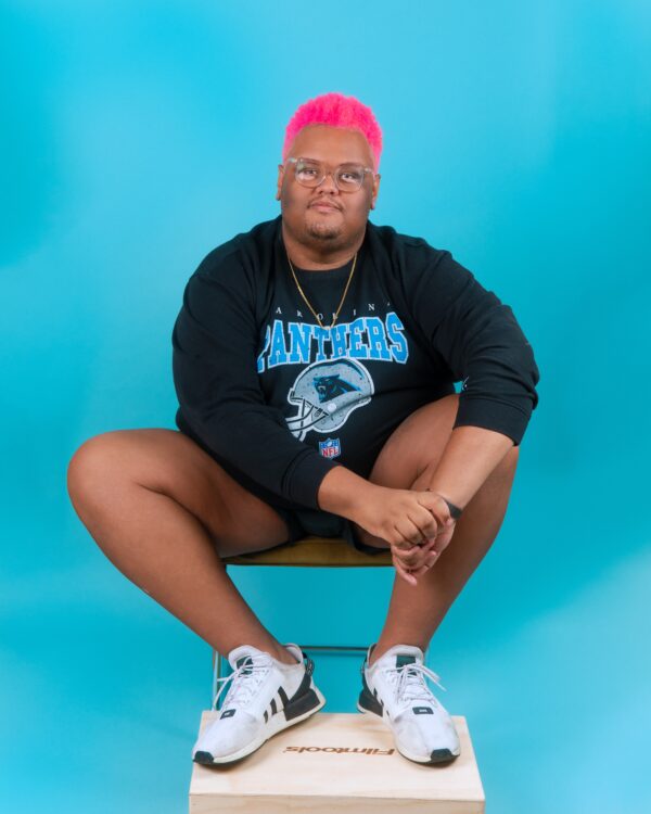 a photo of cody ziglar sitting on a chair with a blue background