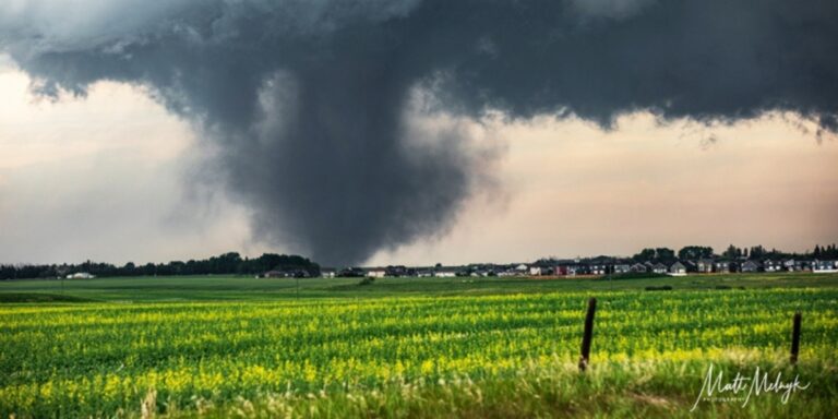 a photo of the tornado in the distance with an open green field in the forefront