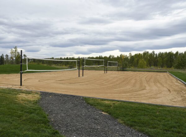 a photo of three outdoor volleyball courts made on a large sand field with three nets 