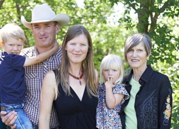 rachel herbert pictured with her family with her husband wearing a white cowboy hat and green trees in the background