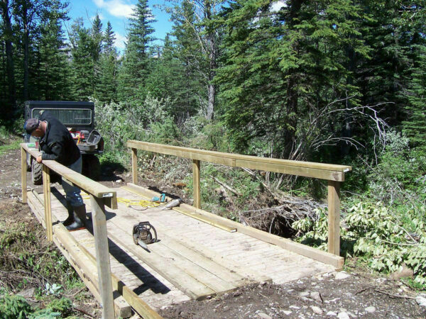 Man working on building a trail bridge for an OHV in the Bighorn Backcoutry of Alberta.