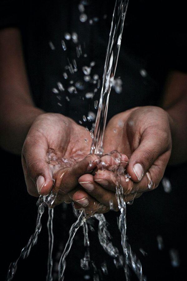 A photo of hands underneath the flow of clean drinking water from a tap.