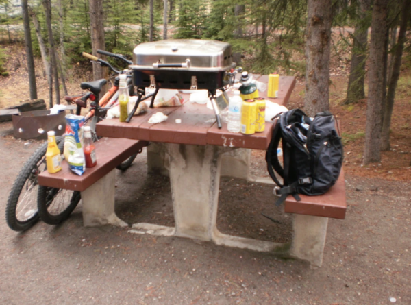 a photo of a picnic table covered in trash and food left by campers