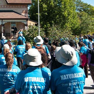 A large crowd of event participants wearing blue shirts outside of a building