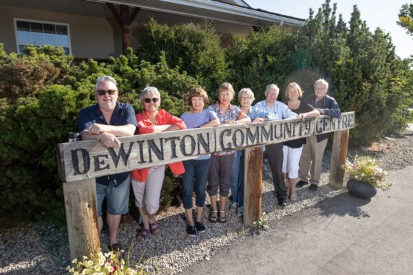 members of the dewinton heritage committee posing for a photo behind the dewinton community centre sign