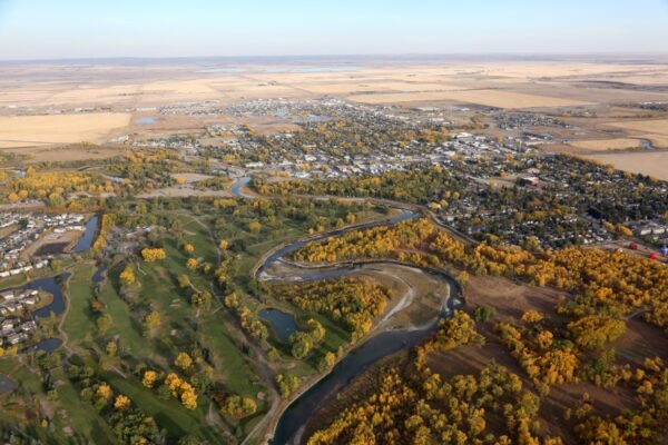 an aerial photo of high river showing the town nestled between trees and a river passing through