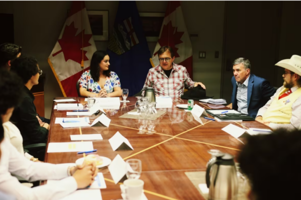 a photo of a group of young people listening to canadas federal minister of natural resources at a table