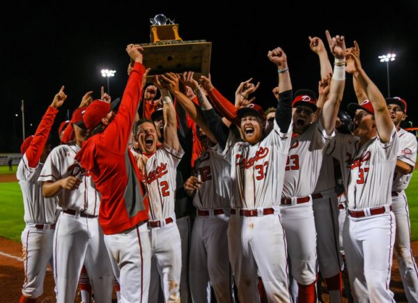 a photo of the okotoks dawgs cheering and holding up a trophy 