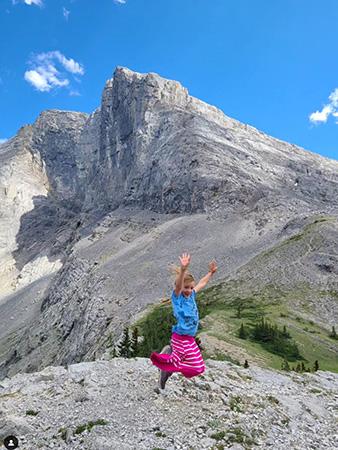 8-year old girl leaping for joy on the summit of Wind Mountqin in Kananaskis