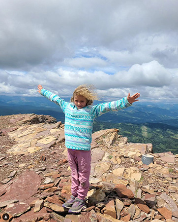 8-year-old girl with arms out in triumph on top of Table Mountain in the Castle Wilderness in Alberta