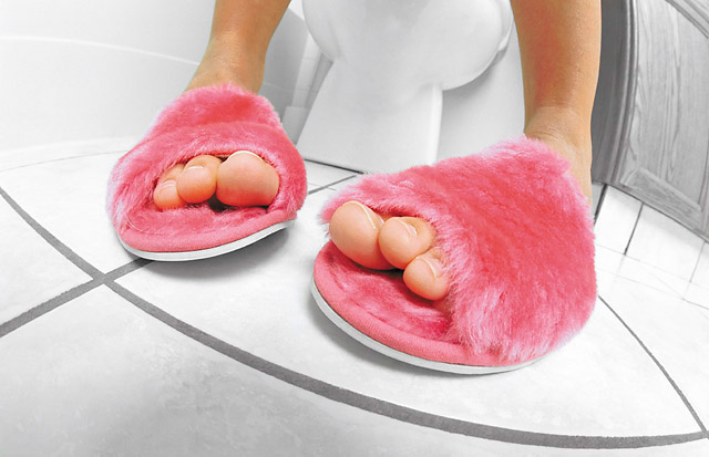Lady sitting on toilet with he feet in pink slippers