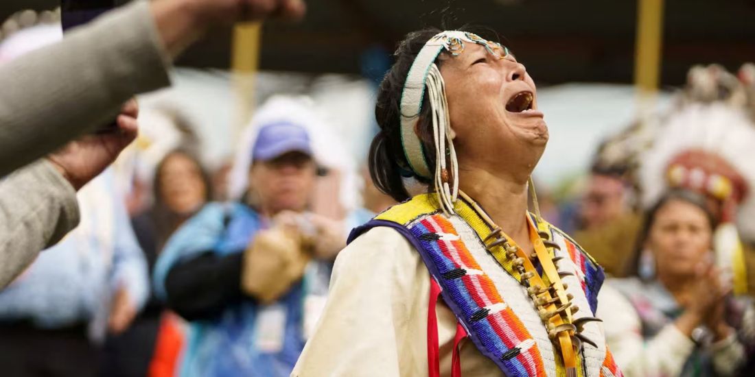 An Indigenous woman at pow wow crying in anguish.